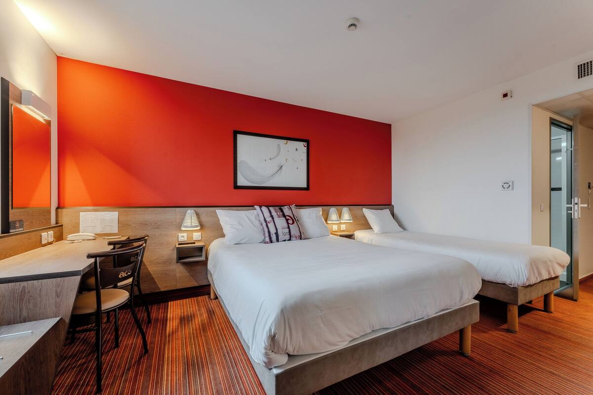 A hotel room with two beds, a desk, and a chair.