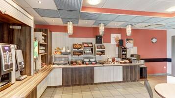 A modern cafe interior with a counter, coffee machines, and various food items displayed.