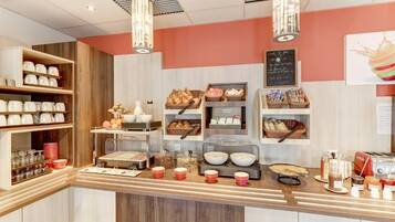 A breakfast buffet area with various food items and serving utensils.