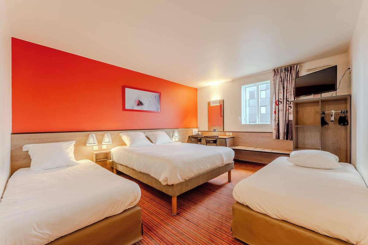 A hotel room with two beds, a desk, a mirror, a TV, and a wardrobe.