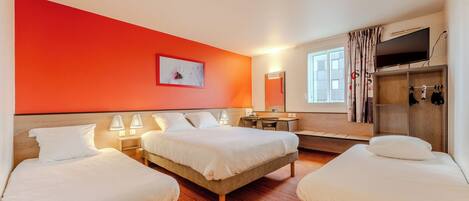 A hotel room with two beds, a desk, a TV, and a window with curtains.