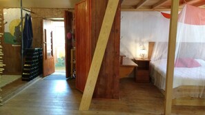 A bedroom with a wooden floor, a bed with a white canopy, a bedside table with a lamp, and a wooden wardrobe. - Termas da Azenha (Soure)