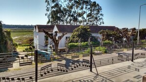 A white building with a tiled roof, surrounded by trees and a fence with musical notes. - Termas da Azenha (Soure)