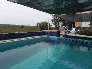 A swimming pool with clear blue water, surrounded by a tiled deck with lounge chairs. - Termas da Azenha (Soure)