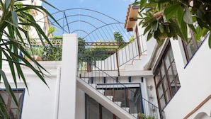 A white building with a balcony, potted plants, and a metal railing. - Hostal Pons (Palma de Mallorca)