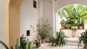 A courtyard with potted plants, a bench, and a staircase leading to an upper level. - Hostal Pons (Palma de Mallorca)