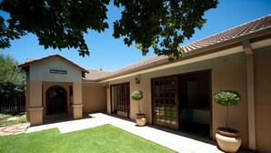 A reception area with a sign, a small lawn, and potted plants. - Rise and Shine Lodge (Bloemfontein)