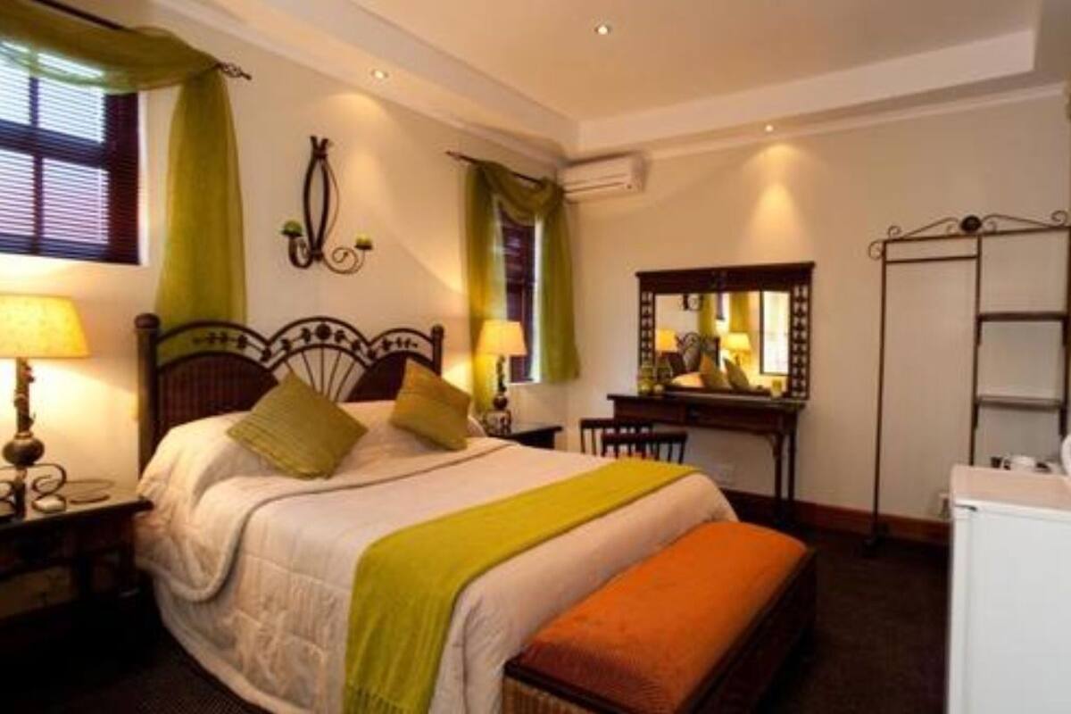 A hotel room with a bed, bedside table, lamp, dresser, mirror, and a television.