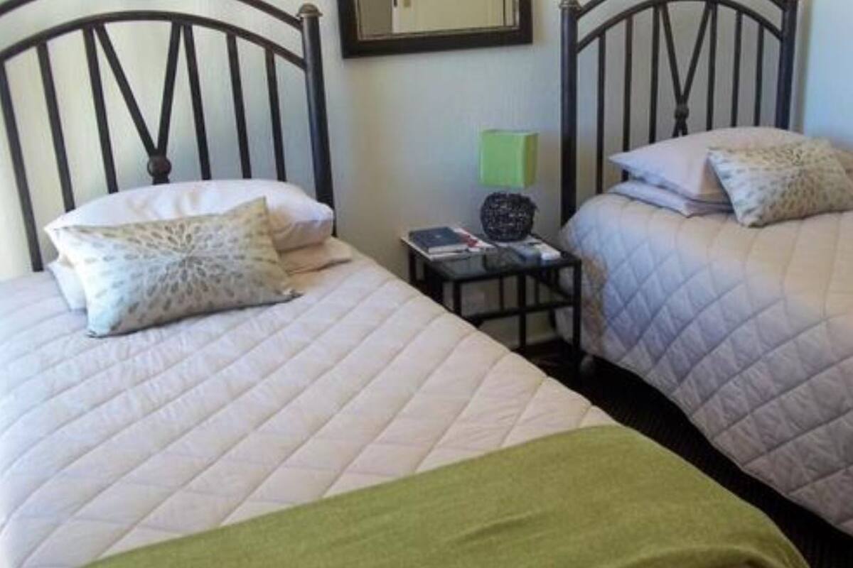 Two twin beds with headboards, a bedside table with a lamp, and a framed picture on the wall.