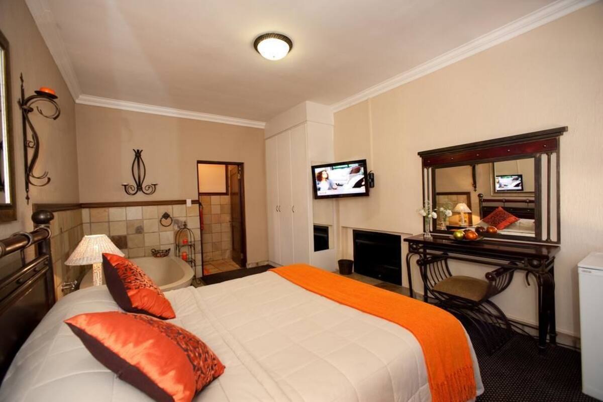 A hotel room with a bed, a desk, a television, a mirror, and a bathroom.
