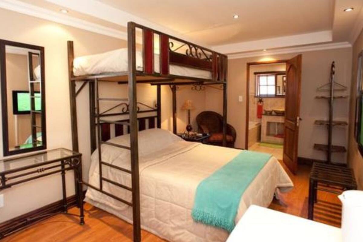 A bunk bed room with a desk, a mirror, a television, and a door leading to another room.