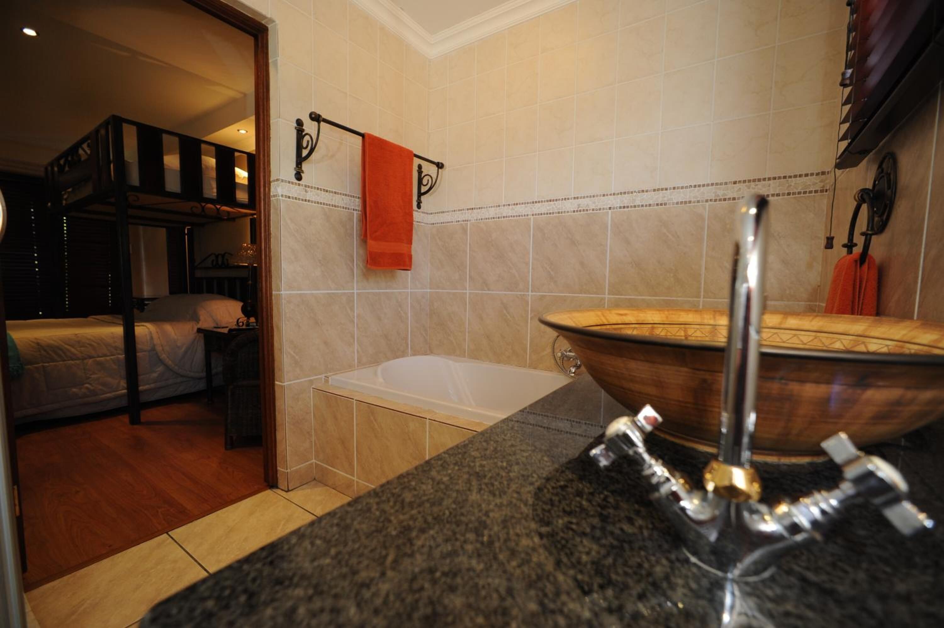 A bathroom with a bathtub, a sink, and a mirror. There is a towel rack with a towel hanging on it.