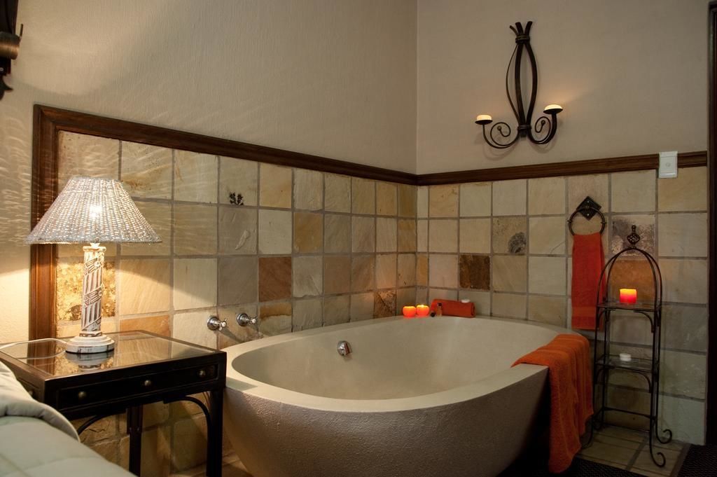 Un baño con una bañera independiente, un tocador con lámpara, y un accesorio de luz empotrado en la pared.