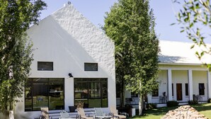 Un edificio moderno blanco con piscina, zona de estar exterior y un elemento decorativo de piedra.