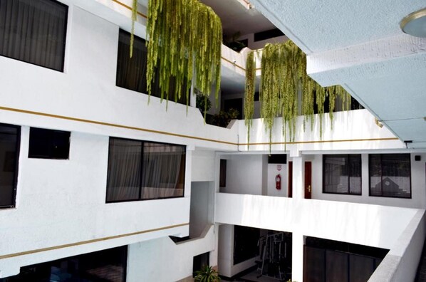 Un edificio de varios niveles con balcones y plantas colgantes.