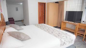 Una habitación de hotel con cama, televisión, armario y escritorio.