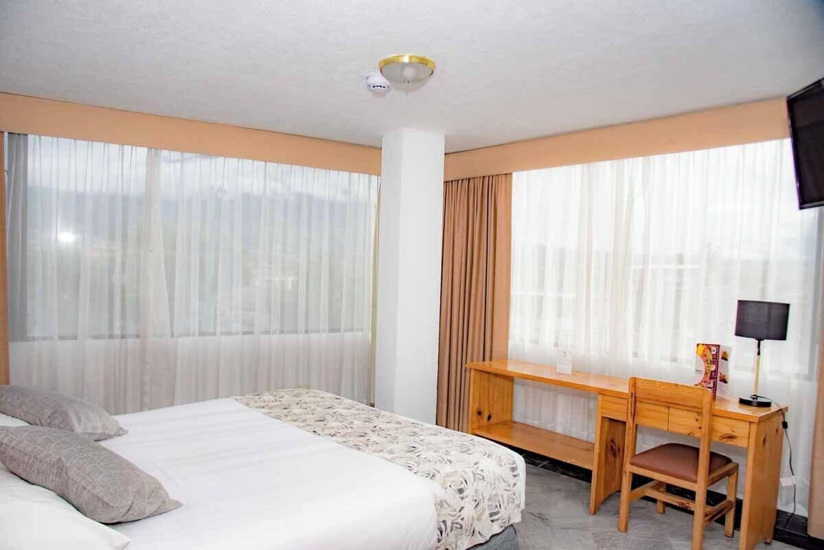 A hotel room with a bed, a desk, and a chair.