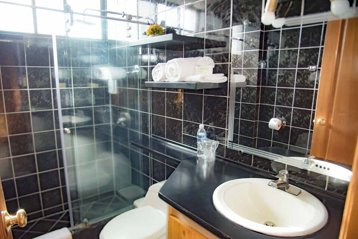 Une salle de bain moderne avec une douche à parois de verre, un lavabo blanc et un plan de toilette noir.