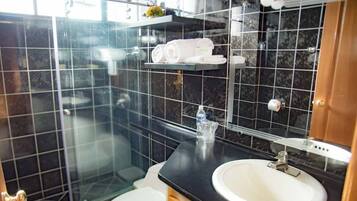 Une salle de bain moderne avec une douche à parois de verre, un lavabo blanc et un plan de toilette noir.