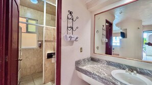 Un baño con lavamanos de mármol, un espejo grande y un perchero para toallas.