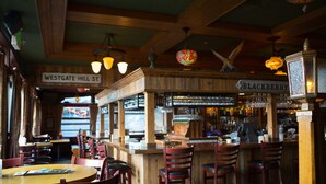 A bar area with wooden furniture, a sign reading "Westgate Hill St.", and a "Blackberry" sign above the bar. - McMenamins Gearhart Hotel (Gearhart)