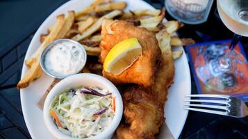 Ein Teller mit Fisch und Pommes, eine kleine Schüssel Krautsalat und ein Getränk.