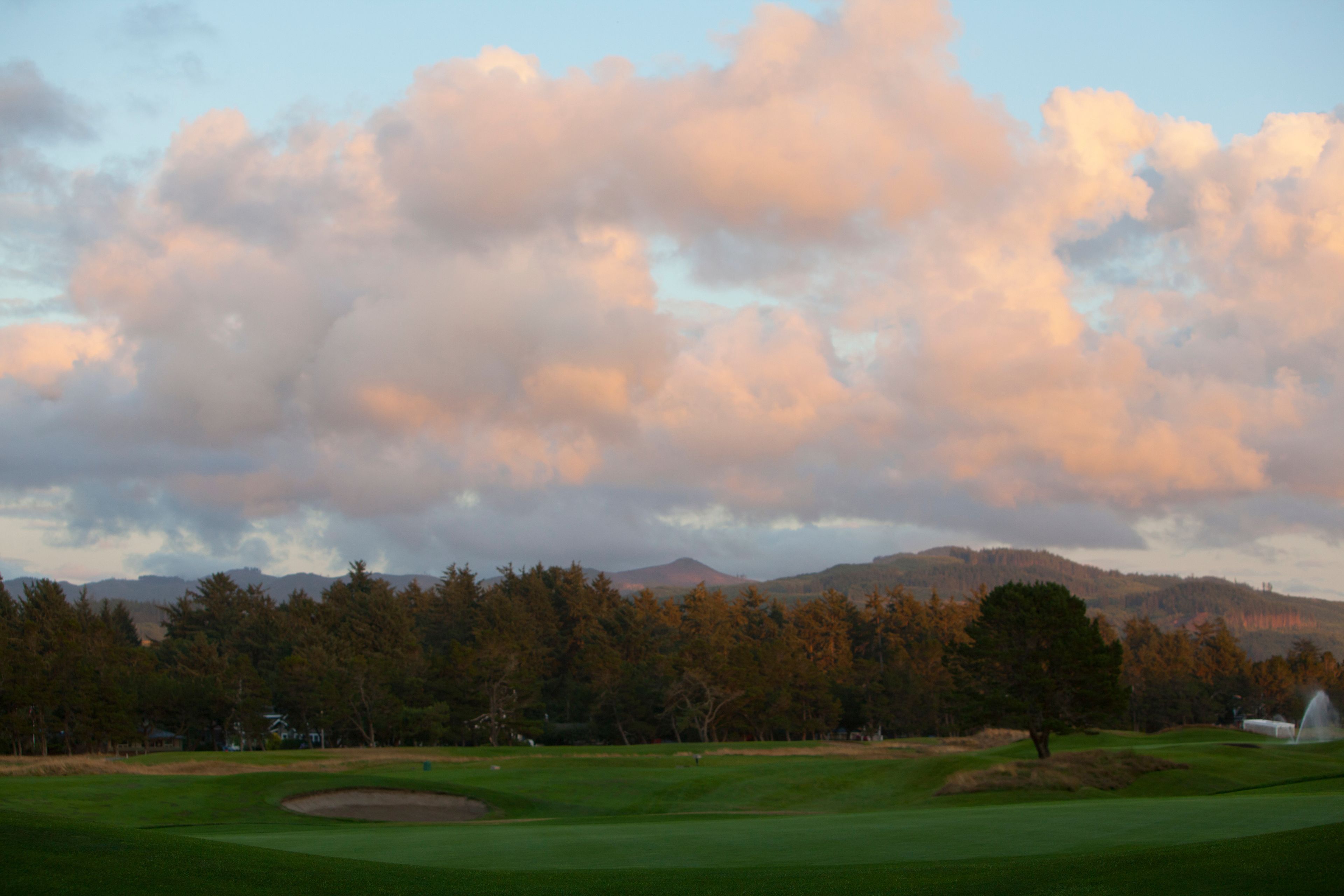 A golf course with a clear sky and mountains in the background.
