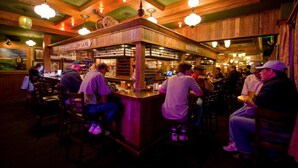 A bar area with wooden decor, bar stools, and patrons. - McMenamins Gearhart Hotel (Gearhart)