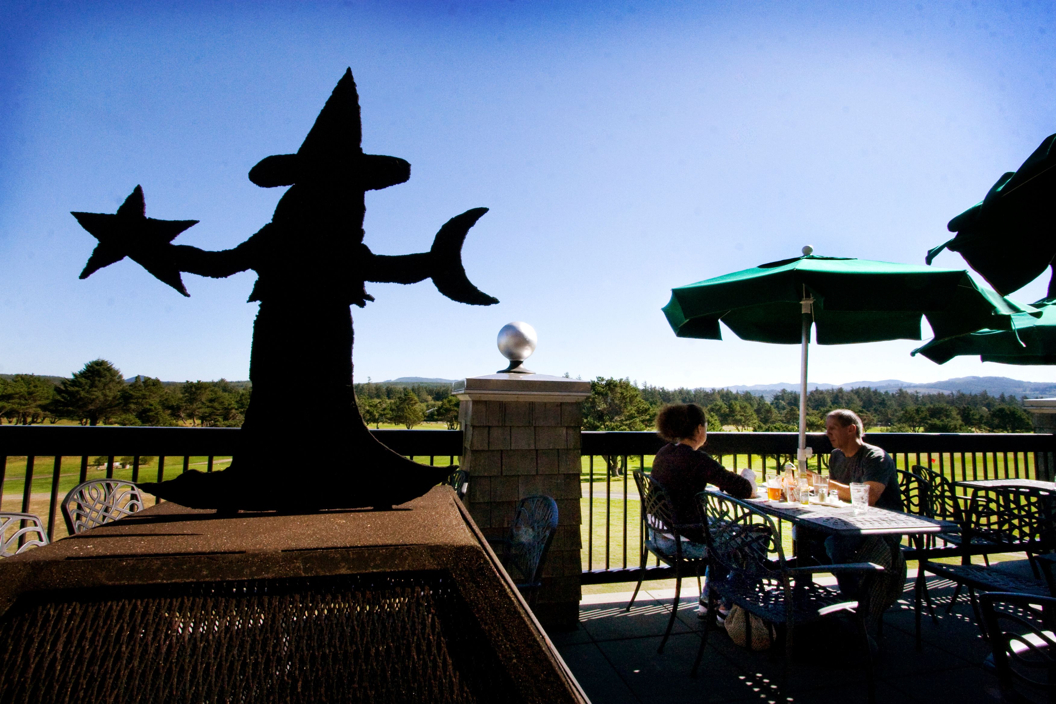 A patio with a decorative witch figure, outdoor seating, and a view of the landscape.