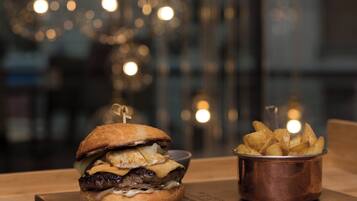A burger with a side of fries on a wooden table.
