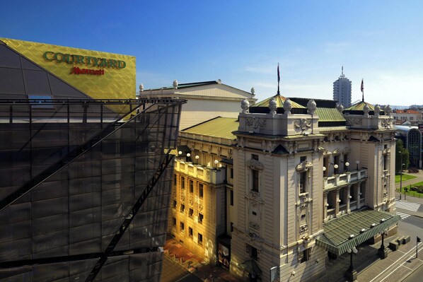 A modern building with a large sign for Courtyard by Marriott. It features a prominent staircase and classical architectural elements.
