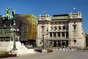 A historic building with classical architecture, a statue of a figure on horseback, and a flag on top.