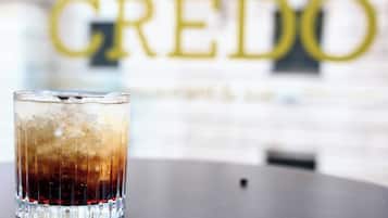 Een glas met een ijskoud drankje op een tafel, met op de achtergrond het woord 'GREDO' dat niet scherp is.