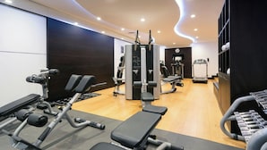 Een moderne sportschool met diverse fitnessapparaten, waaronder een bankdrukapparaat, krachttoestellen en een loopband.