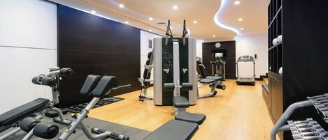 A modern gym with various exercise equipment, including a bench press, weight machines, and a treadmill.