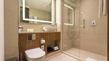 A modern bathroom with a glass-enclosed shower, a wooden vanity, and a large mirror.