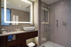 A modern bathroom with a large mirror, a glass shower enclosure, and a wooden vanity.