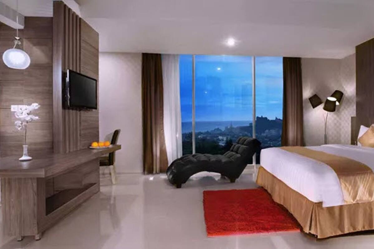 Una habitación de hotel moderna con una cama grande, un escritorio, un televisor y vistas a la ciudad.