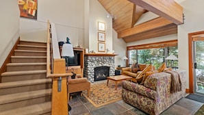 A spacious living area with a fireplace, a sofa, a coffee table, and a staircase. - Montebello by Whistler Premier (Whistler)