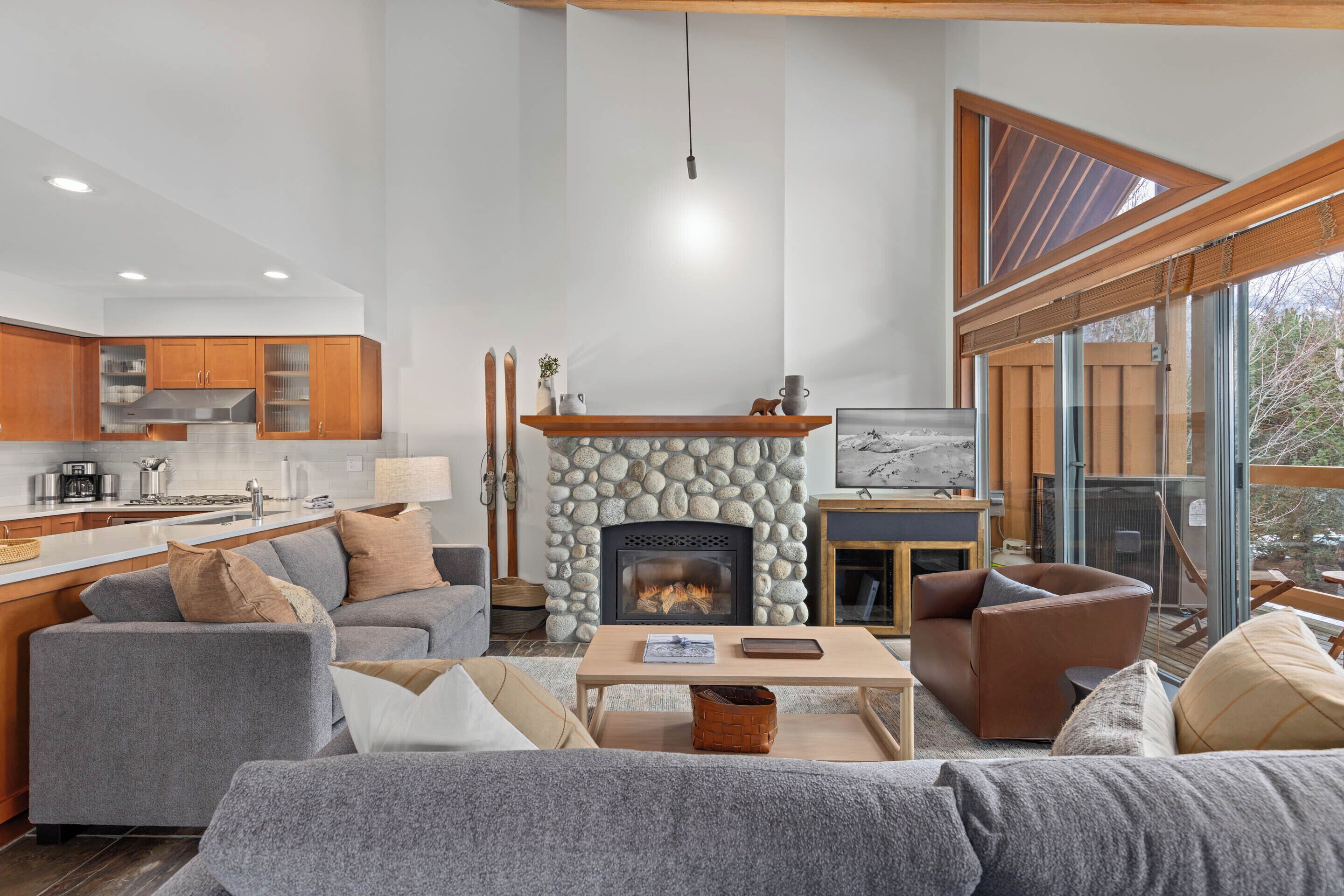 A modern living room with a stone fireplace, grey sofas, and a wooden coffee table.