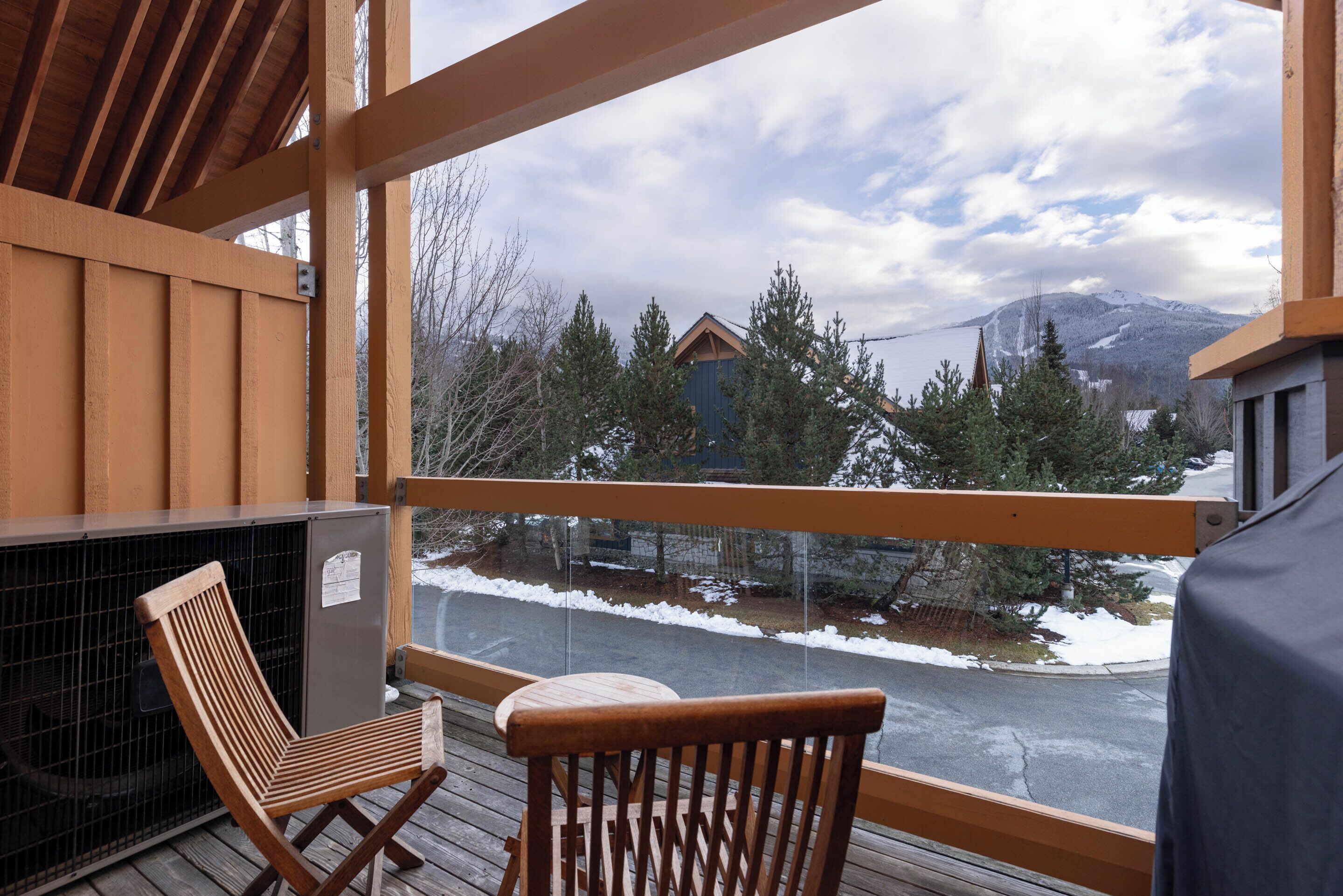 Eine Holzterrasse mit Blick auf eine verschneite Landschaft und Berge.