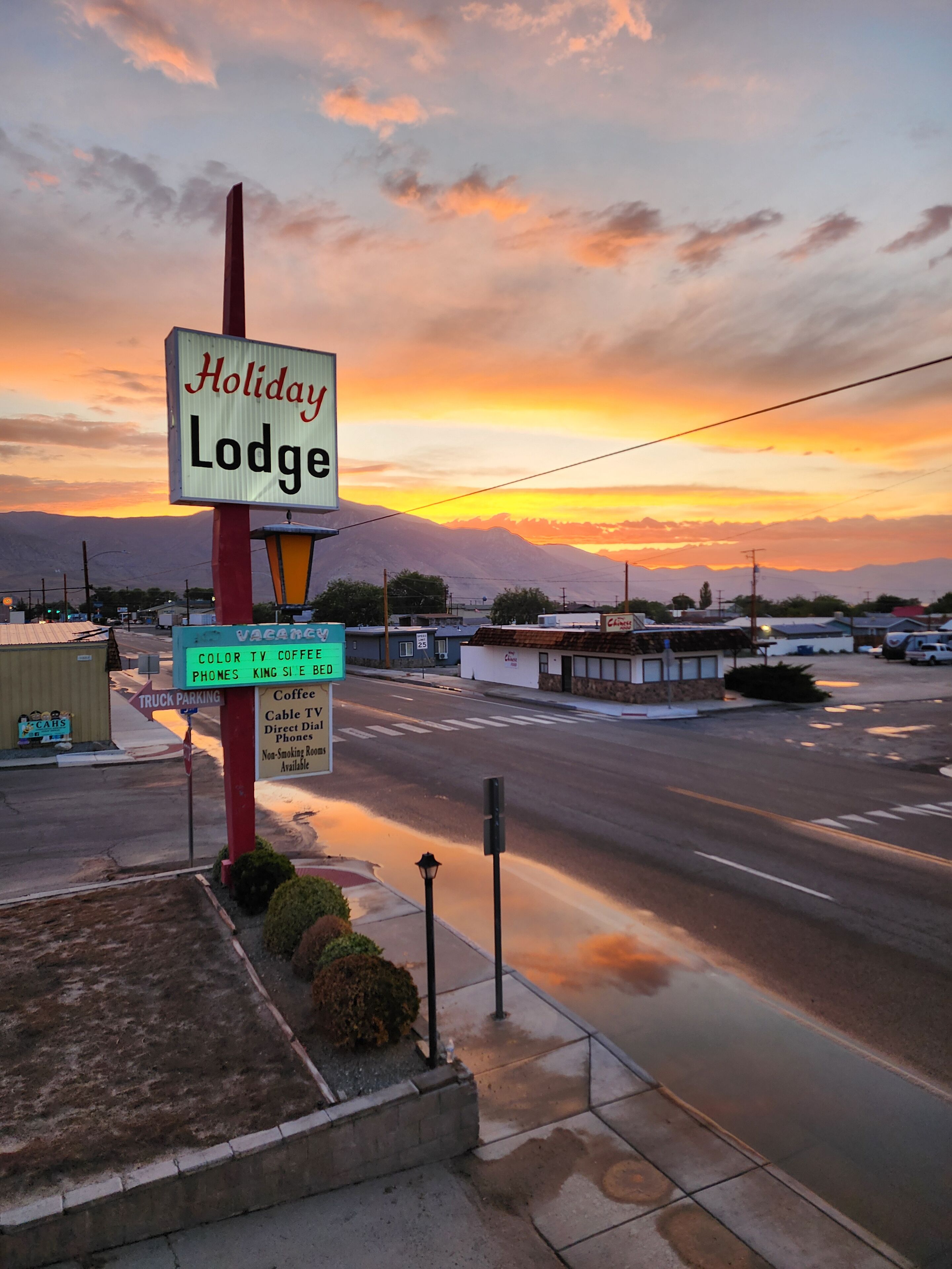 A Holiday Lodge sign with amenities including color TV, coffee, and phones.