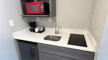 A compact kitchen with a built-in microwave, a sink, and a dishwasher.