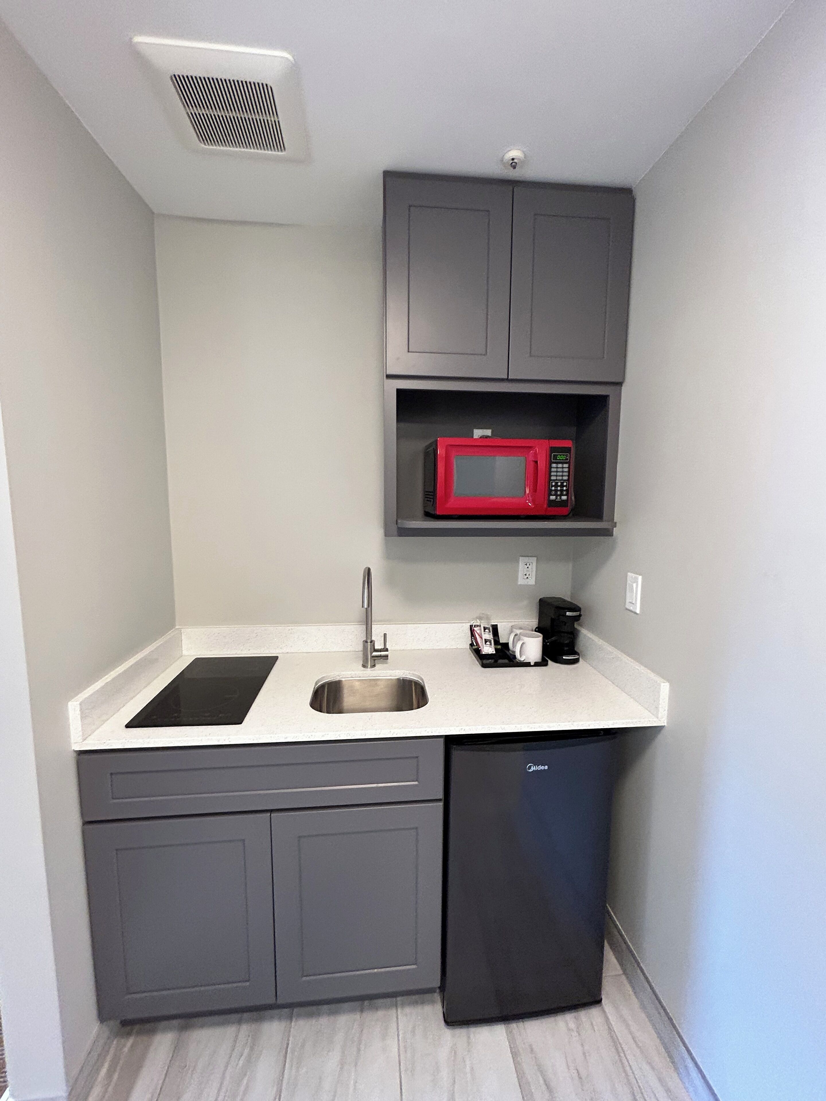 A compact kitchen with a built-in microwave, a sink, and a dishwasher.
