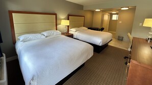 Ein Hotelzimmer mit zwei Betten, einem Schreibtisch und einem Stuhl.