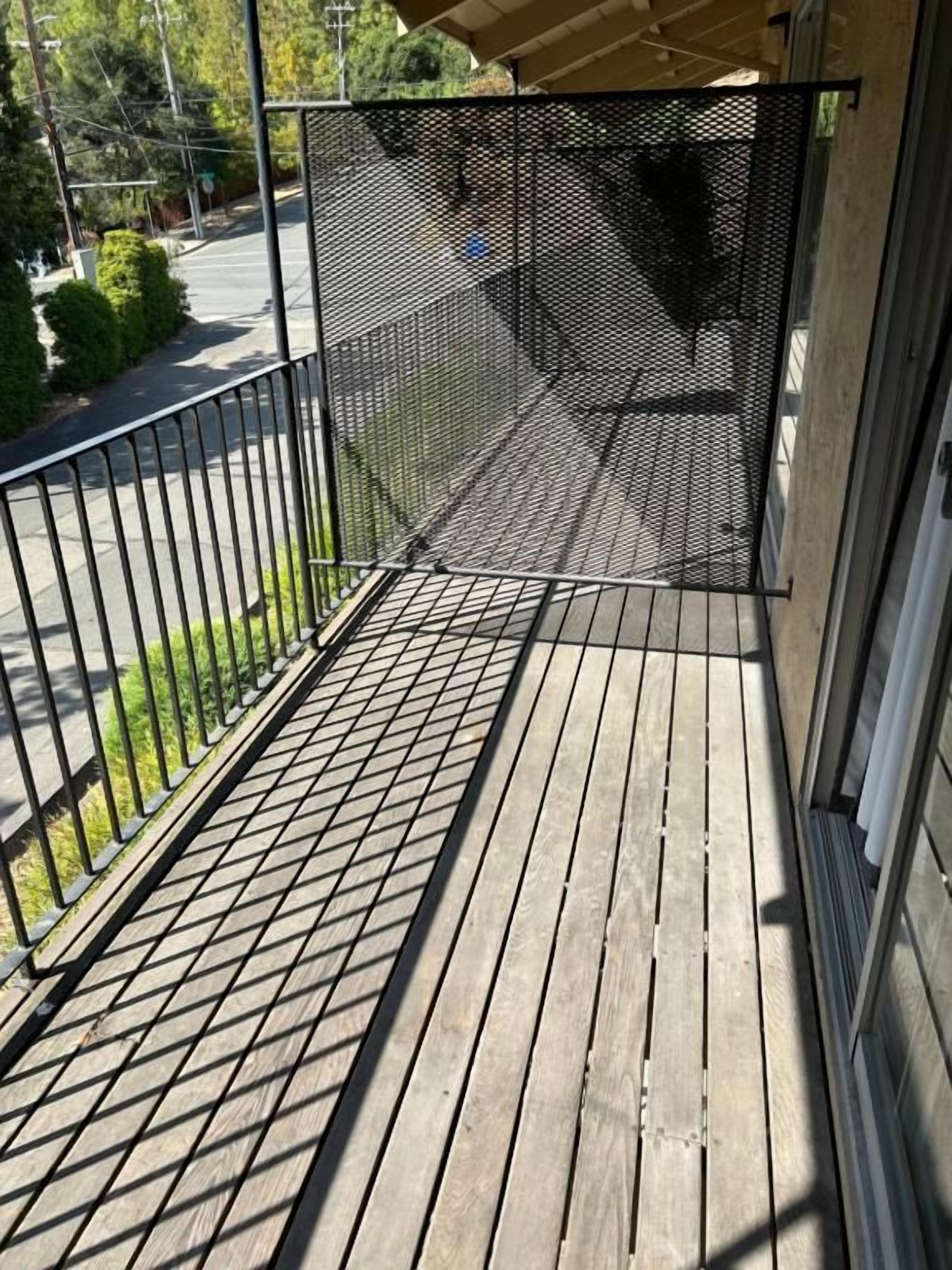 A wooden deck with a metal railing and a mesh screen.
