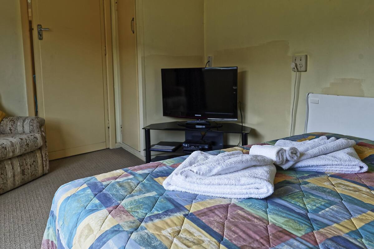 Ein Hotelzimmer mit Bett, Fernseher und einer Couch.