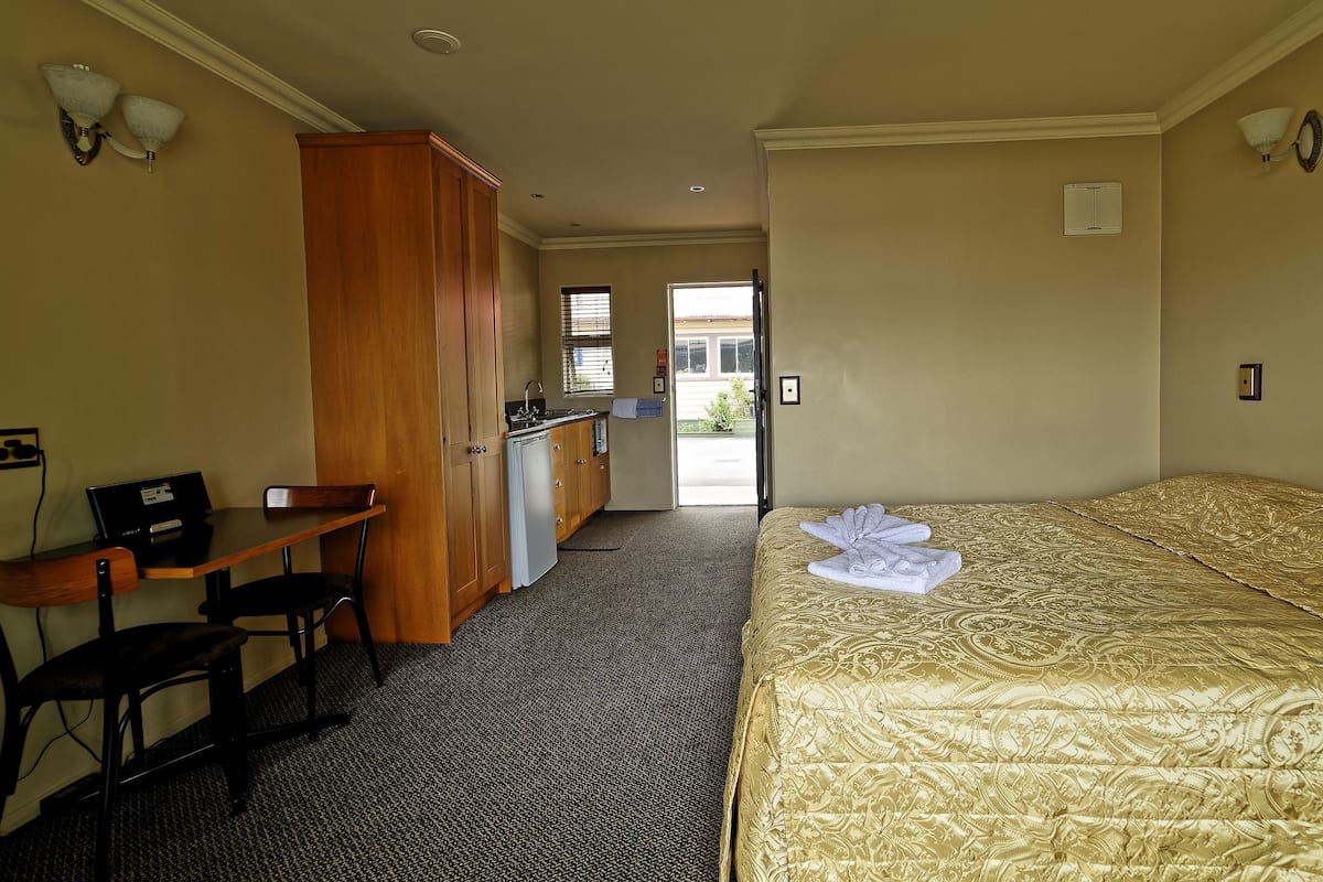 Ein Hotelzimmer mit Bett, Schreibtisch, Kleiderschrank und einer Küchenzeile.