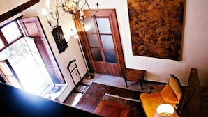 Une pièce avec une porte en bois, un lustre, une tapisserie et un canapé.
