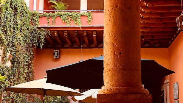 Une cour avec des sièges en plein air, une colonne et un espace abrité.